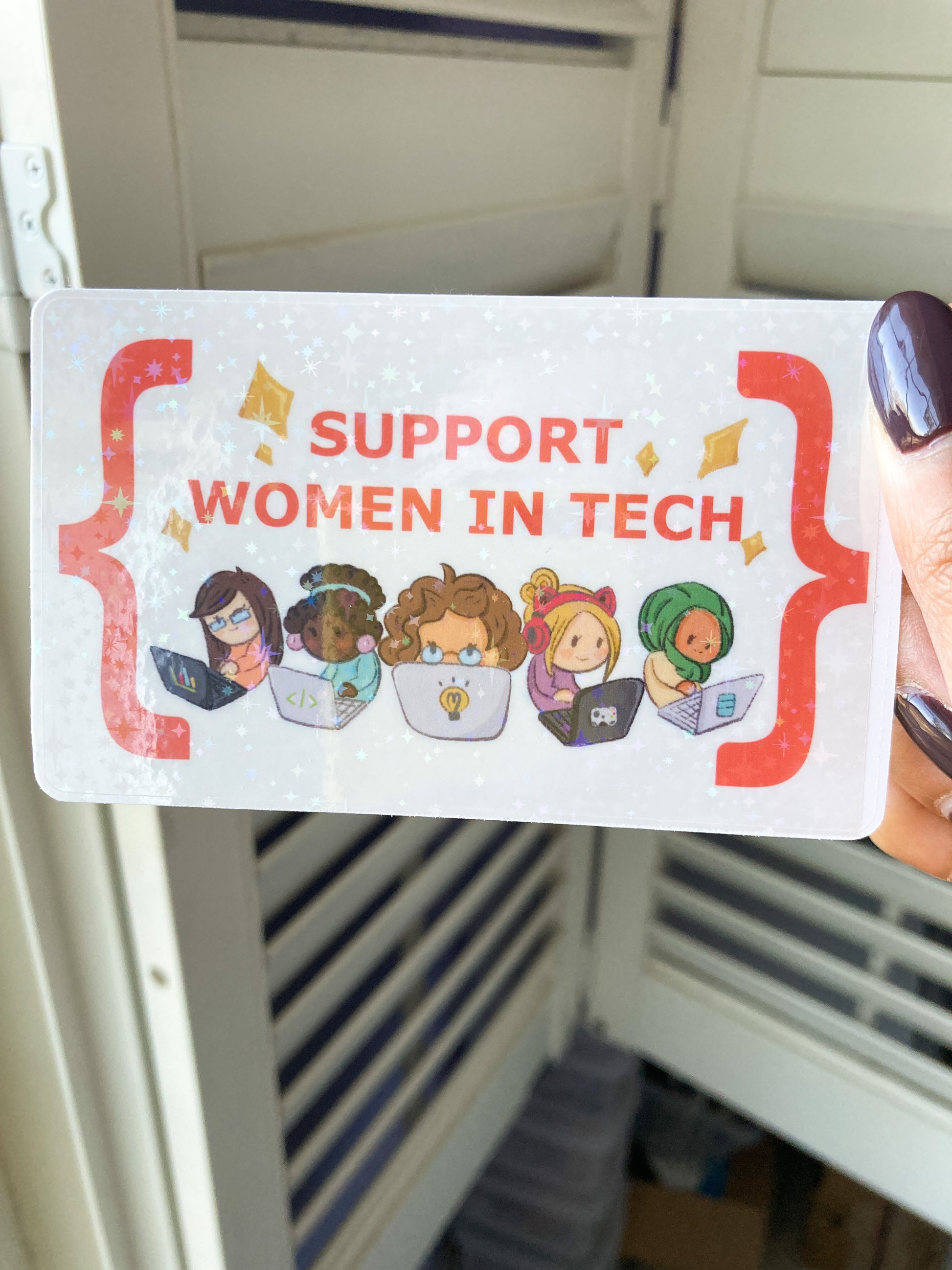 Sticker with 'Support Women in Tech' text and illustrations of women using technology, held in front of a locker.