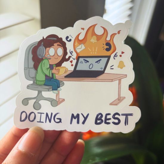 Sticker of a person at a desk with text 'Doing my best' held by a hand.